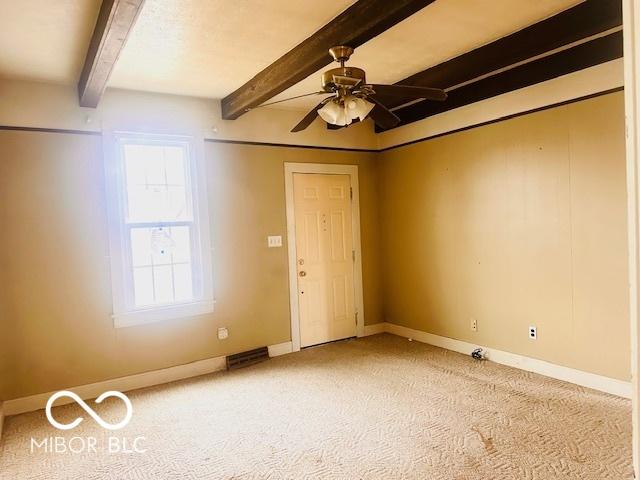 empty room featuring baseboards, beamed ceiling, and a ceiling fan