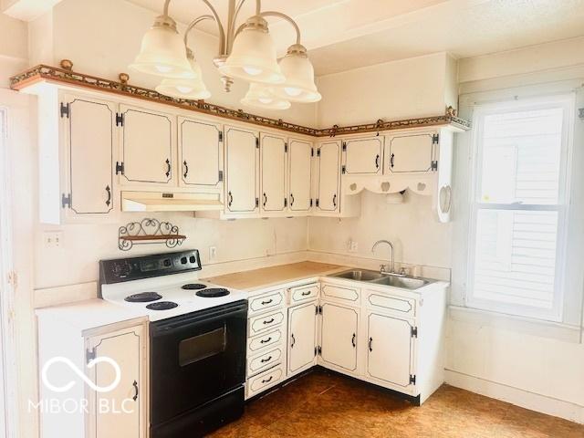 kitchen featuring range with electric stovetop, dark tile patterned floors, light countertops, under cabinet range hood, and a sink