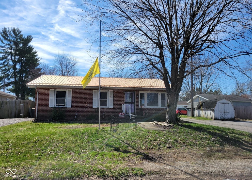 ranch-style home with brick siding, a storage unit, an outbuilding, and fence