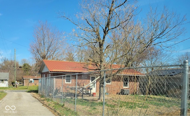 view of front of house with fence, brick siding, and metal roof