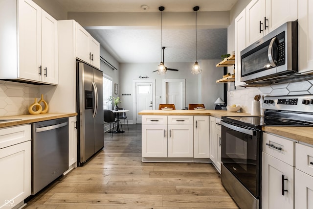 3732 N Kenwood Ave, Indianapolis, IN 46208 - kitchen featuring stainless steel appliances, wooden counters, a peninsula, light wood-type flooring, and hanging light fixtures