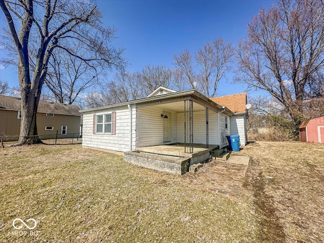 view of front facade with a front yard, an attached carport, fence, an outdoor structure, and a storage shed