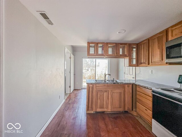 kitchen with visible vents, a sink, stainless steel microwave, range with electric stovetop, and a peninsula
