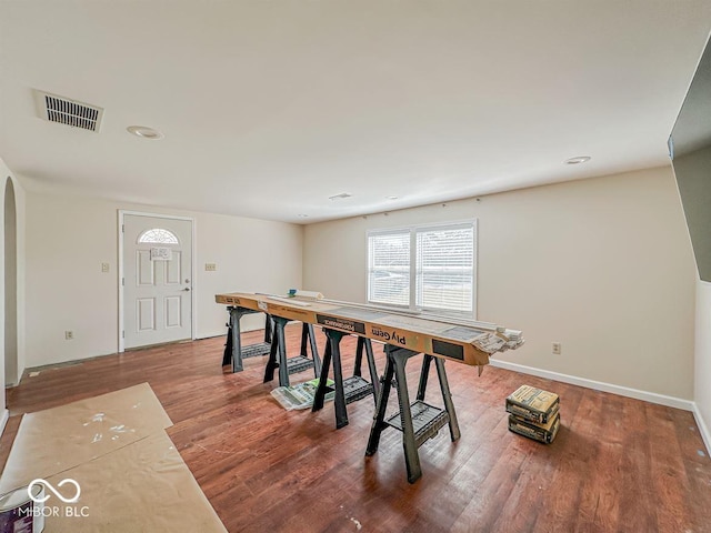 dining space featuring visible vents, arched walkways, baseboards, and wood finished floors