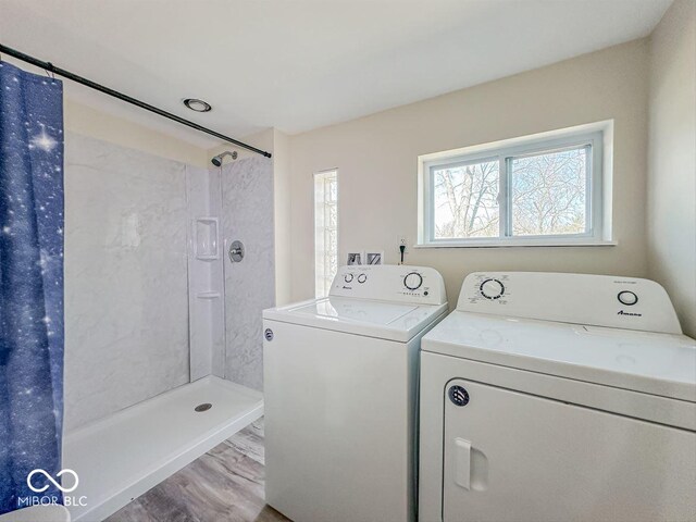 clothes washing area with washer and dryer, laundry area, and wood finished floors