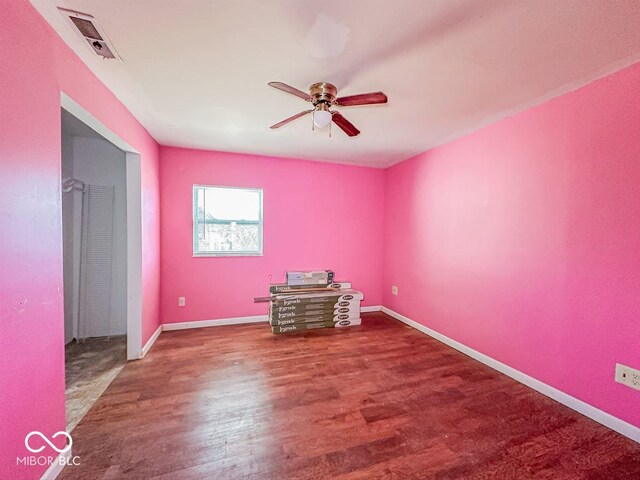 unfurnished room featuring baseboards, wood finished floors, visible vents, and ceiling fan