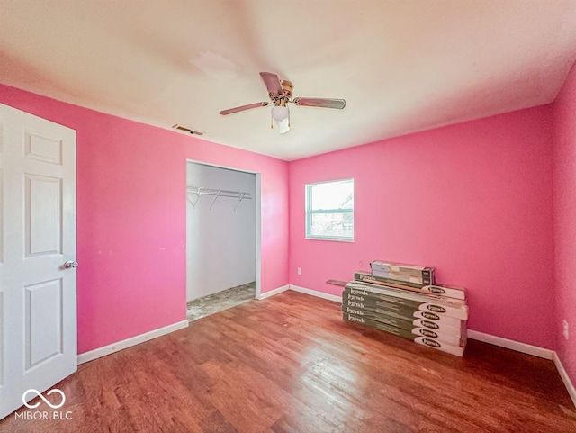 unfurnished bedroom featuring a closet, visible vents, baseboards, and wood finished floors