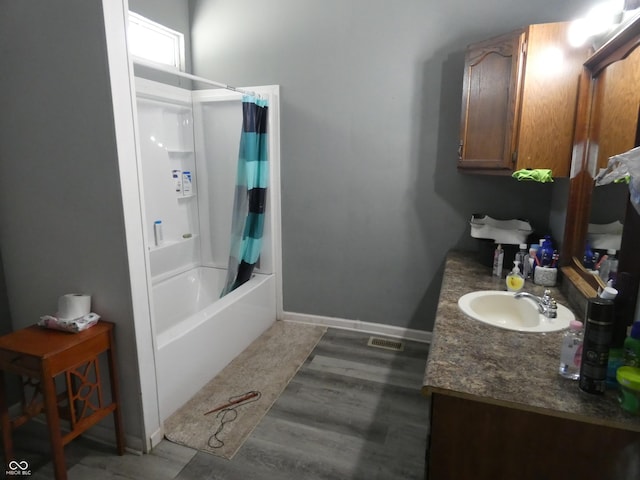 full bath featuring visible vents, shower / bath combo, wood finished floors, baseboards, and vanity