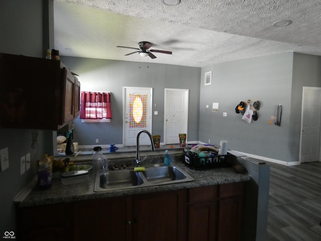 kitchen with dark countertops, visible vents, ceiling fan, a textured ceiling, and a sink