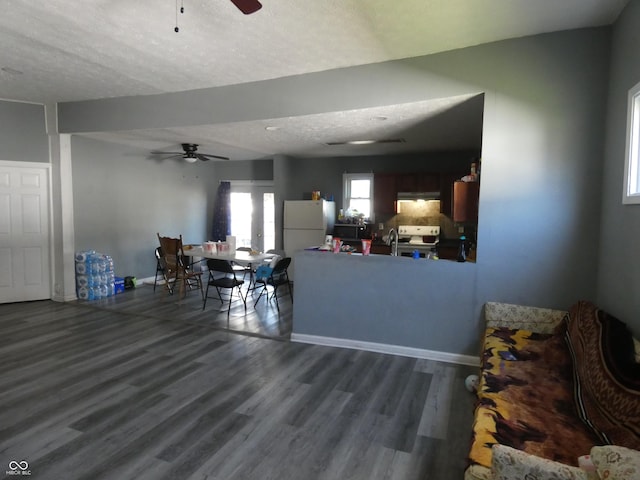 living area with baseboards, a textured ceiling, wood finished floors, and a ceiling fan