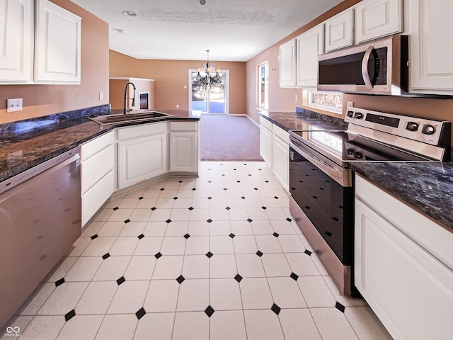 kitchen with a sink, stainless steel appliances, a notable chandelier, and white cabinetry