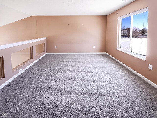 carpeted empty room with baseboards and vaulted ceiling