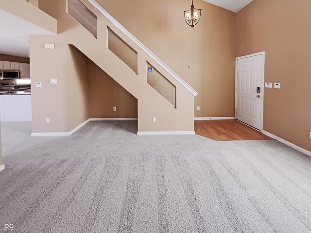 unfurnished living room featuring baseboards, a chandelier, and light carpet