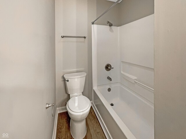 full bath featuring shower / bath combination, wood finished floors, baseboards, and toilet