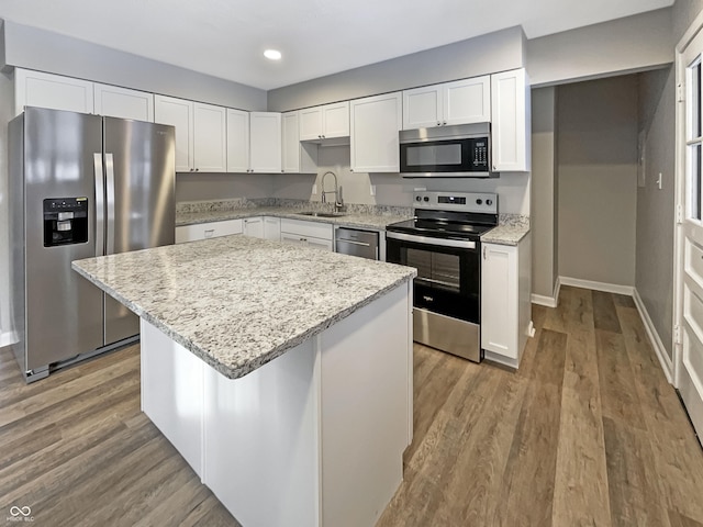 kitchen with a sink, white cabinetry, appliances with stainless steel finishes, light stone countertops, and recessed lighting