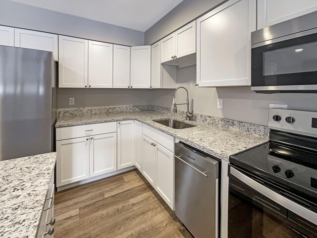 kitchen with white cabinets, light wood-style floors, appliances with stainless steel finishes, and a sink
