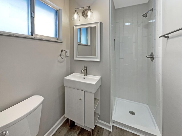 full bath featuring baseboards, toilet, wood finished floors, and a stall shower
