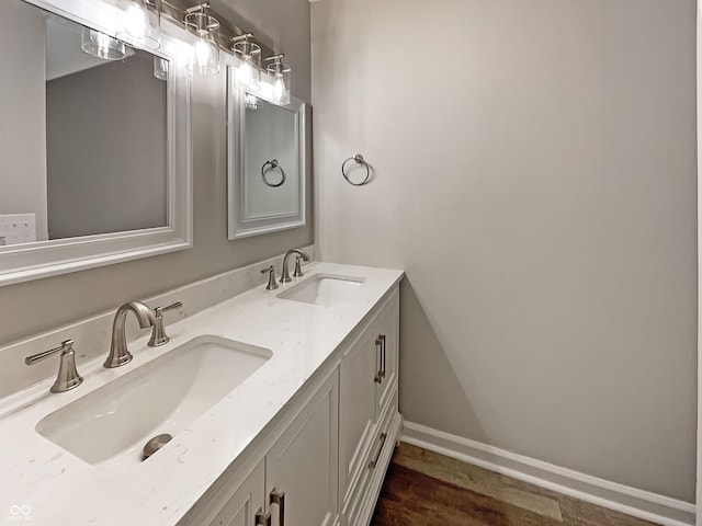 bathroom featuring baseboards, wood finished floors, a sink, and double vanity