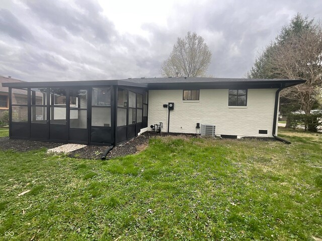 back of property featuring a sunroom, a yard, central AC, and brick siding