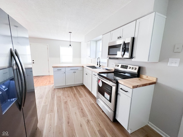 kitchen featuring a sink, wood counters, appliances with stainless steel finishes, and light wood-style flooring