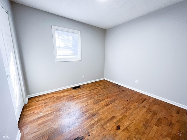 spare room featuring visible vents, baseboards, and wood finished floors
