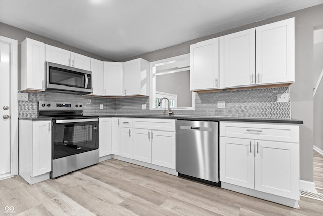 1641 Whistler Ter, Indianapolis, IN 46229 - kitchen featuring appliances with stainless steel finishes, a sink, dark countertops, and light wood-style flooring