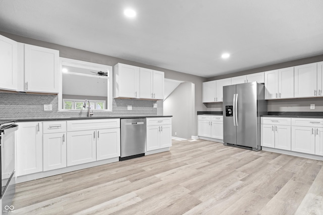 1641 Whistler Ter, Indianapolis, IN 46229 - kitchen with stainless steel appliances, a sink, backsplash, dark countertops, and light wood-style flooring