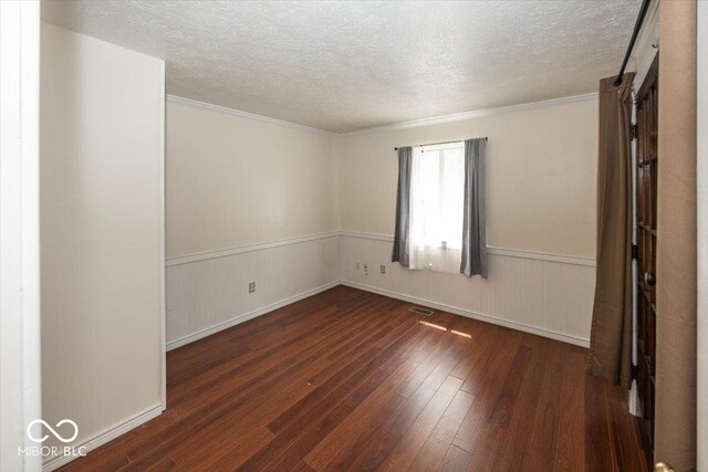 7965 Benjamin Dr, Lawrence, IN 46226 - empty room with hardwood / wood-style flooring, a textured ceiling, wainscoting, and ornamental molding