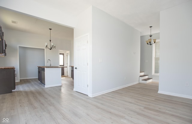 249 N Hamilton Ave, Indianapolis, IN 46201 - unfurnished living room featuring a chandelier, a sink, stairway, and light wood-type flooring