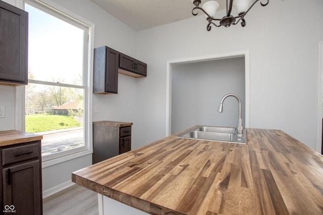 249 N Hamilton Ave, Indianapolis, IN 46201 - kitchen with dark brown cabinets, a sink, wood counters, light wood finished floors, and a notable chandelier