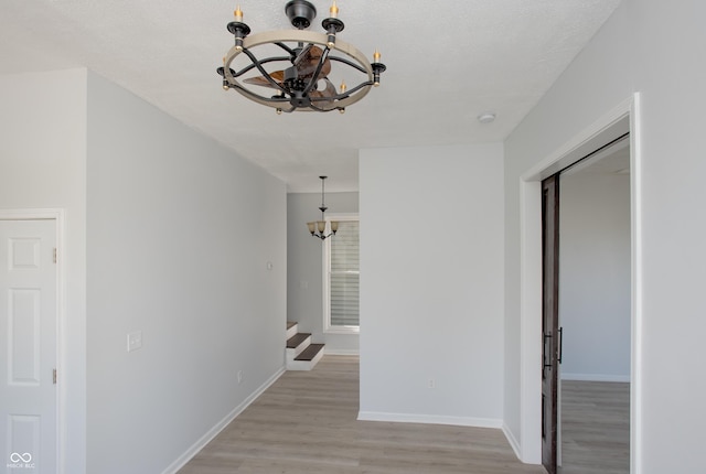249 N Hamilton Ave, Indianapolis, IN 46201 - hallway featuring baseboards, a notable chandelier, light wood-style flooring, and stairway