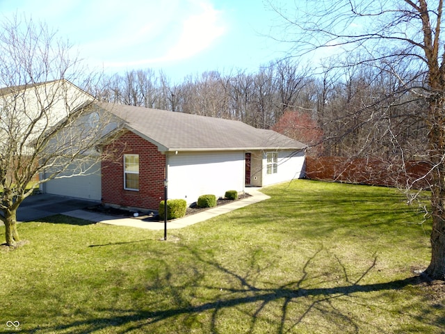 view of side of home with brick siding, an attached garage, and a yard
