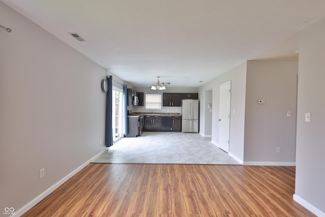 5944 Edelle Dr, Indianapolis, IN 46237 - unfurnished living room with light wood finished floors, visible vents, baseboards, and an inviting chandelier
