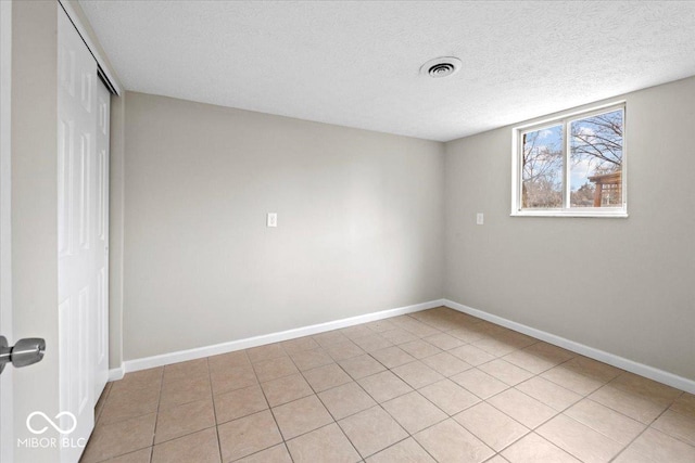 unfurnished room featuring light tile patterned floors, visible vents, baseboards, and a textured ceiling