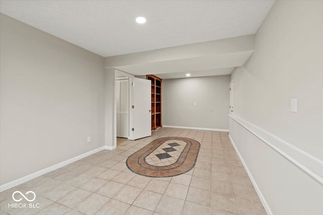 spare room with light tile patterned floors, recessed lighting, baseboards, and a textured ceiling