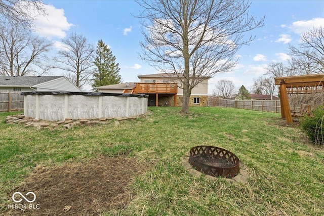 view of yard featuring a covered pool, a deck, a fire pit, and a fenced backyard