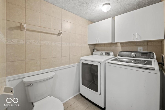 laundry room featuring a textured ceiling, washing machine and dryer, tile walls, light tile patterned floors, and laundry area