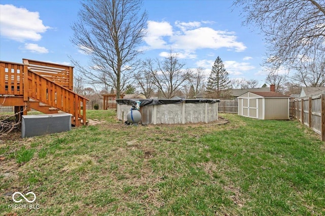view of yard featuring a covered pool, a storage unit, an outbuilding, and a fenced backyard
