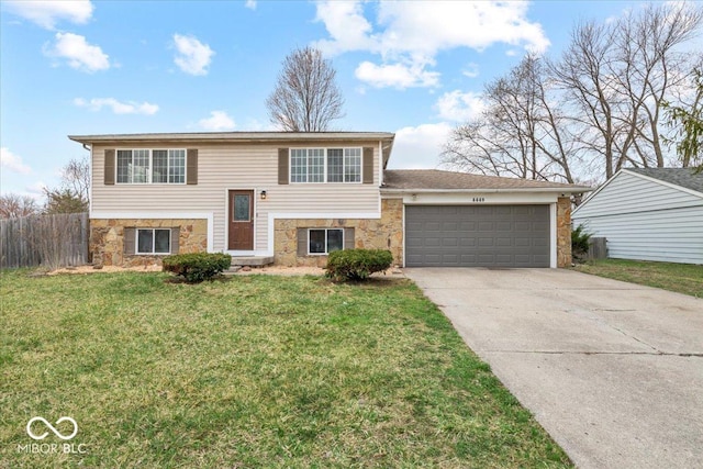 bi-level home featuring a front lawn, fence, concrete driveway, stone siding, and an attached garage
