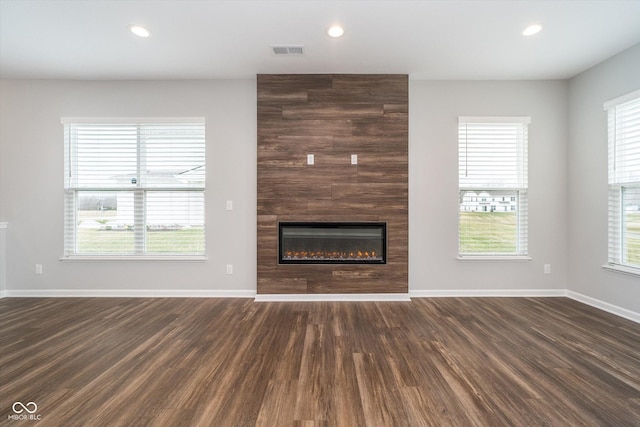unfurnished living room with a large fireplace, visible vents, baseboards, recessed lighting, and dark wood-style floors