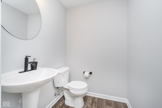 bathroom with toilet, baseboards, and wood finished floors