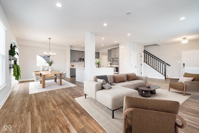 living room featuring stairs, wood finished floors, recessed lighting, and an inviting chandelier