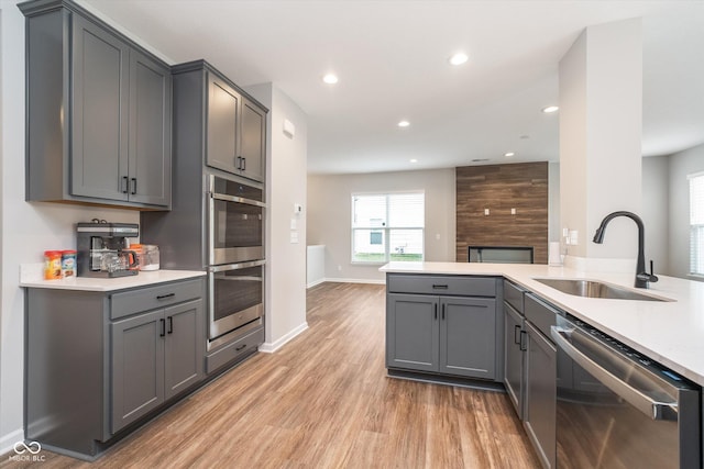kitchen with light countertops, gray cabinets, a sink, and stainless steel appliances