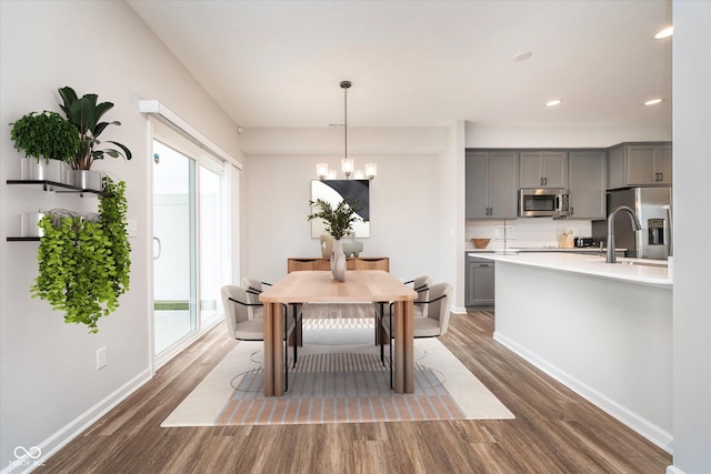 dining room with dark wood-style floors, recessed lighting, baseboards, and an inviting chandelier