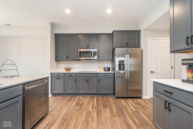 kitchen with light countertops, gray cabinets, stainless steel appliances, and light wood-type flooring