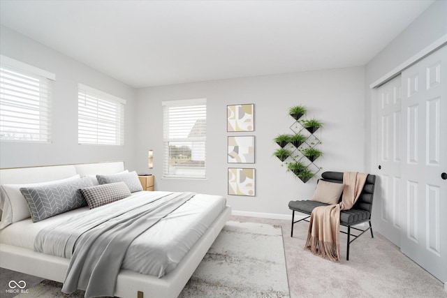 bedroom featuring light colored carpet, a closet, and baseboards