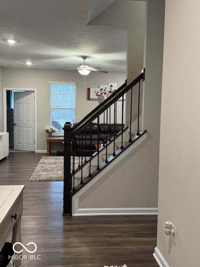 staircase with baseboards, a textured ceiling, ceiling fan, and wood finished floors