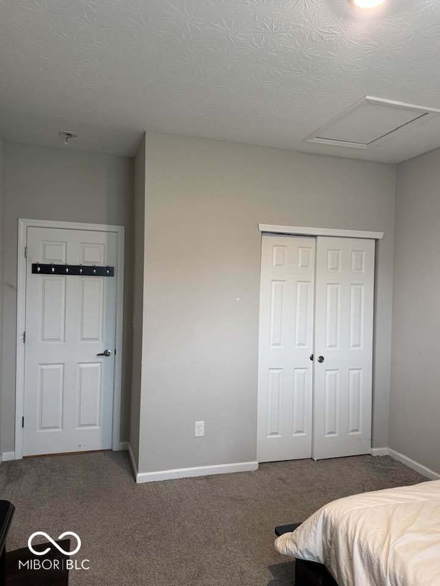carpeted bedroom with a closet, baseboards, and a textured ceiling