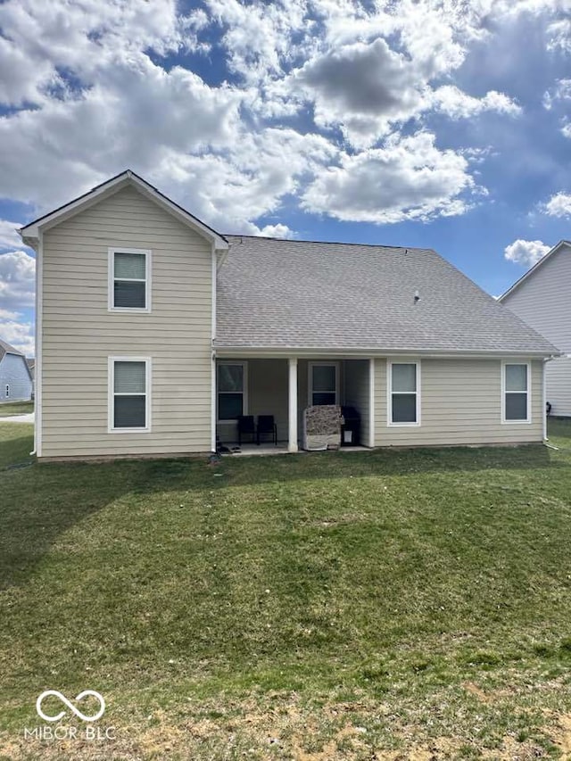 back of property with a patio, a shingled roof, and a yard