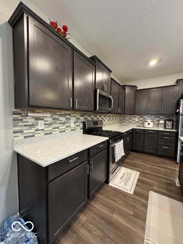 kitchen with dark wood-type flooring, light countertops, stainless steel appliances, and backsplash